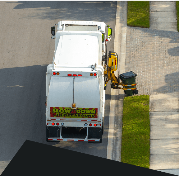 Garbage truck collecting trash on residential street.
