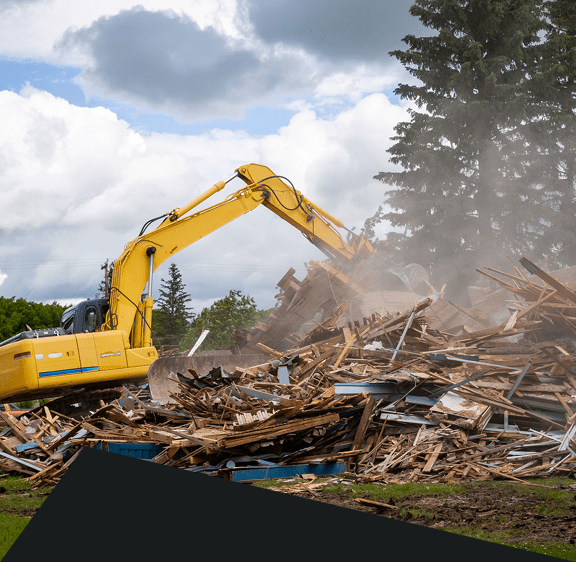 Excavator demolishing building amidst debris and dust.