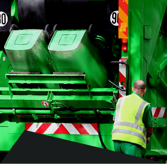 Worker operating a green garbage truck.