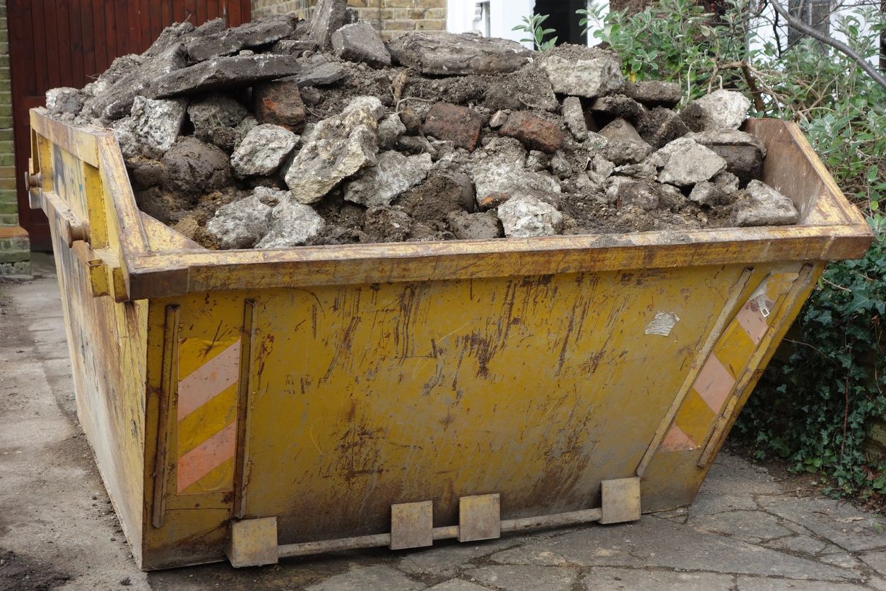 A yellow dumpster filled with rubble and stones.