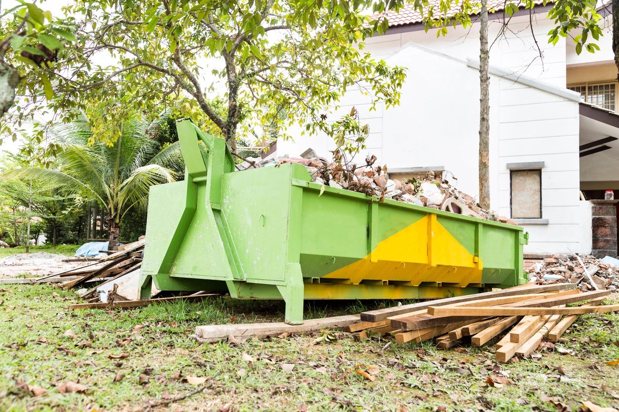 Green and yellow dumpster filled with construction debris outdoors.
